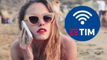 Una ragazza sulla spiaggia con il telefono e, in evidenza, il logo di TIM