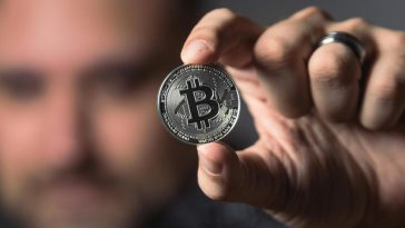 Un uomo mostra un Bitcoin