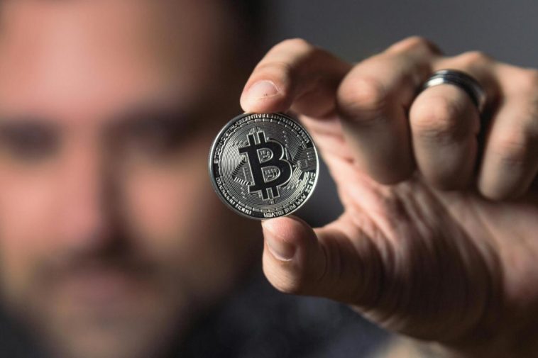 Un uomo mostra un Bitcoin
