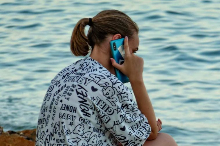 Una ragazza che parla al telefono al mare