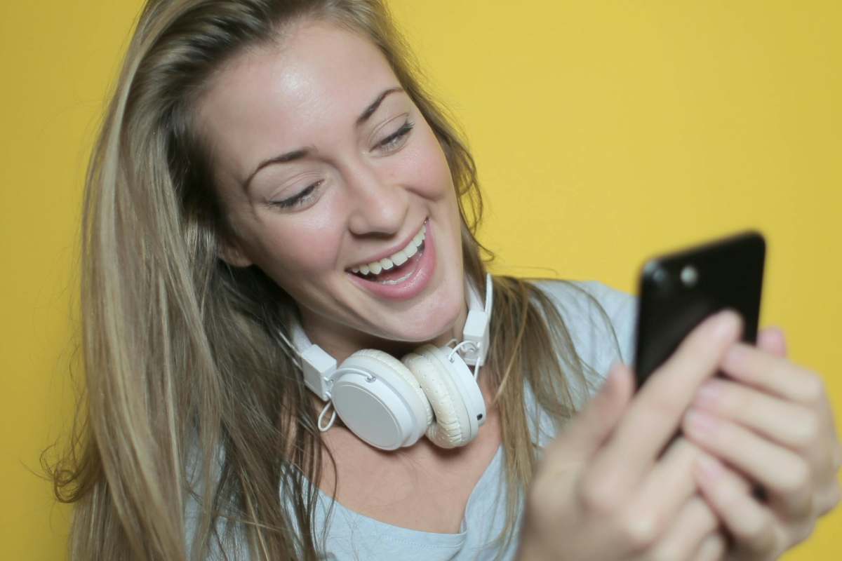 Ragazza con le cuffie che guarda il telefonino e ride