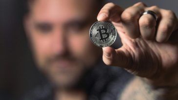 Un uomo mostra un bitcoin