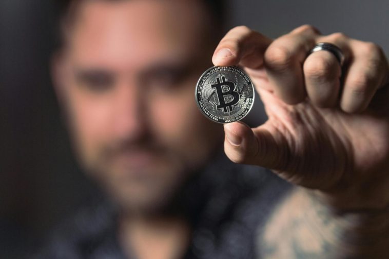 Un uomo mostra un bitcoin