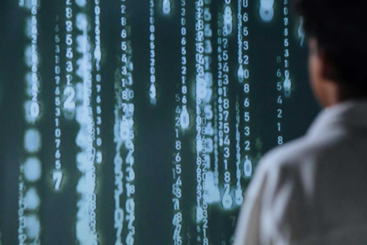 Una persona di fronte a una cascata di dati binari