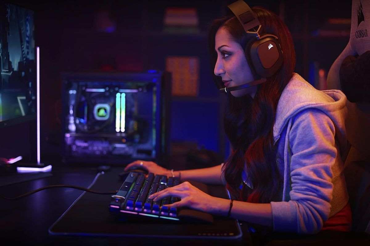 ragazza con cuffie seduta davanti a PC mentre digita su tastiera