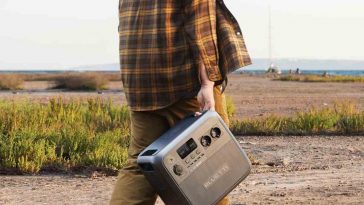 persona cammina nel bosco con centrale elettrca in mano