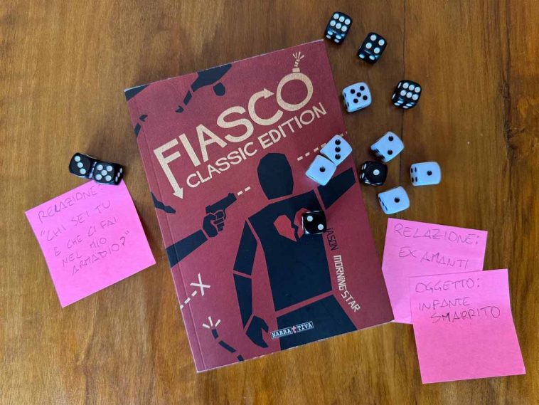 Manuale del GDR Fiasco circondato da dadi a 6 facce e post-it
