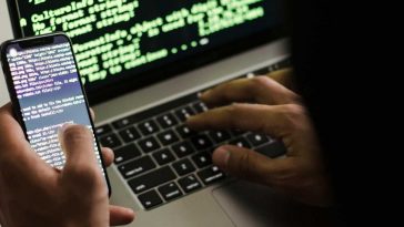 Un hacker con laptop e telefonino