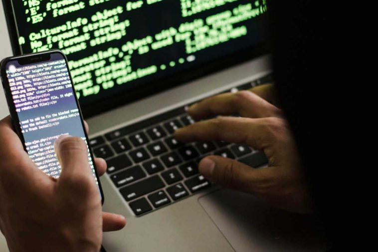 Un hacker con laptop e telefonino