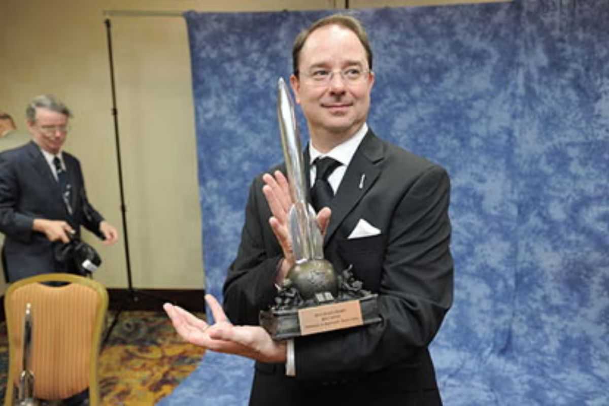 uomo tiene in mano trofeo oblungo