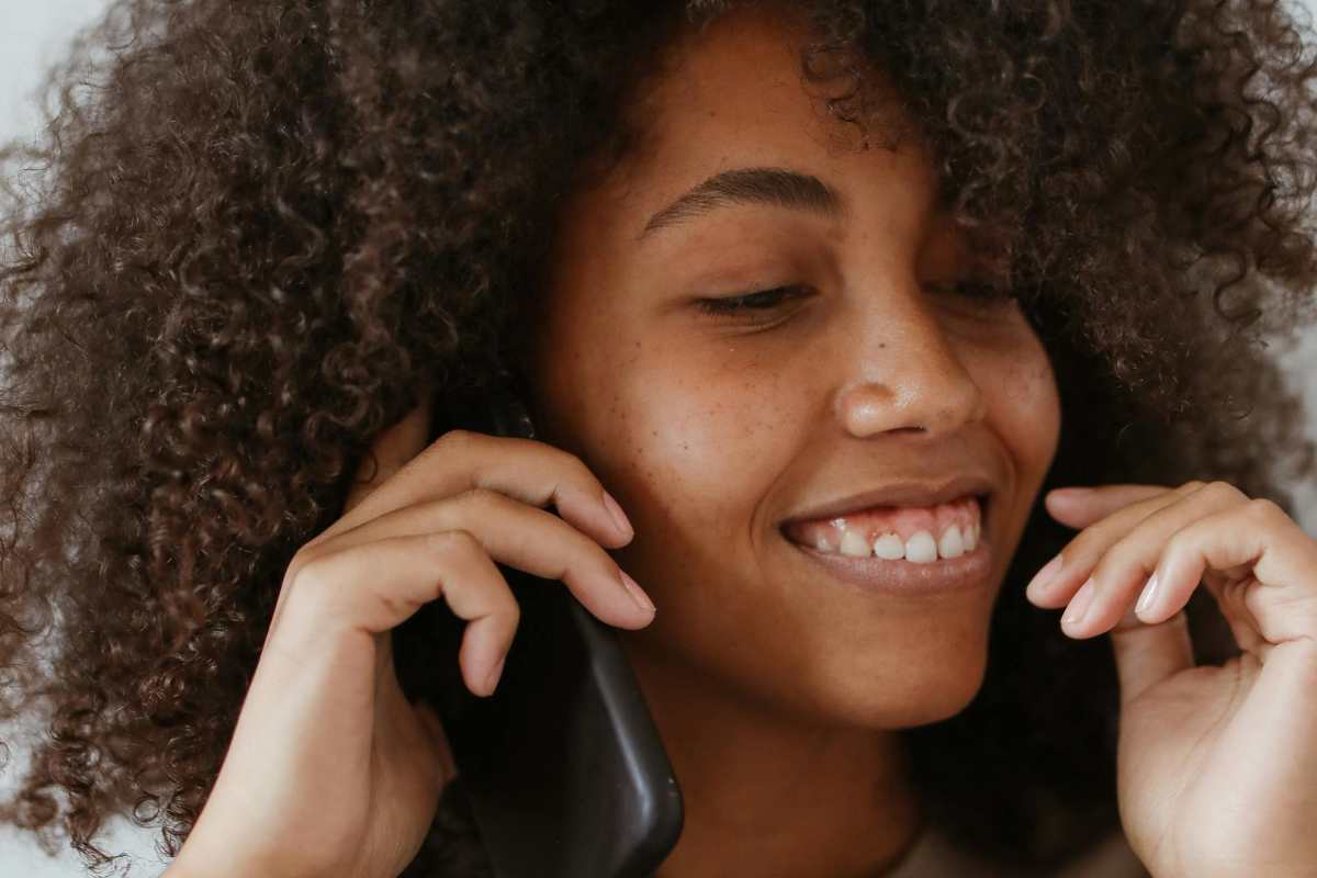 Ragazza con i capelli ricci che parla al telefono