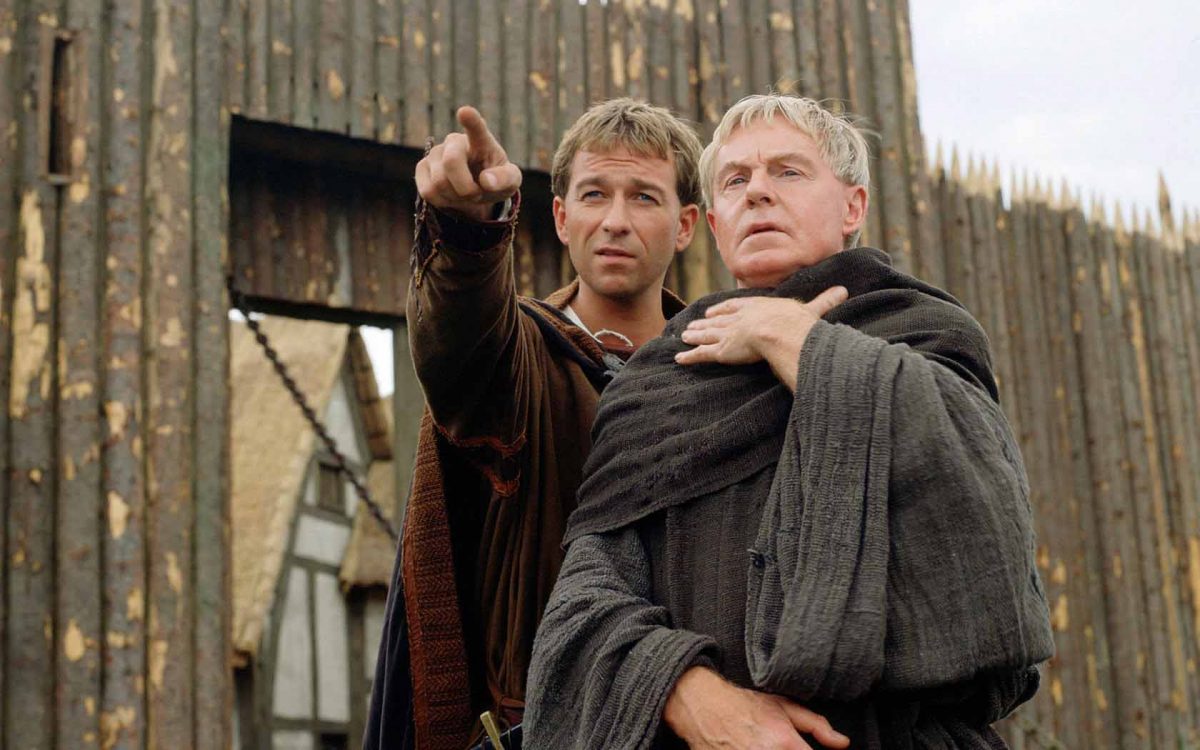 Un estratto dallo show televisivo Cadfael - I misteri dell'abbazia, con due frati davanti una palizzata medievale di legno