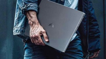 uomo cammina con laptop sotto braccio