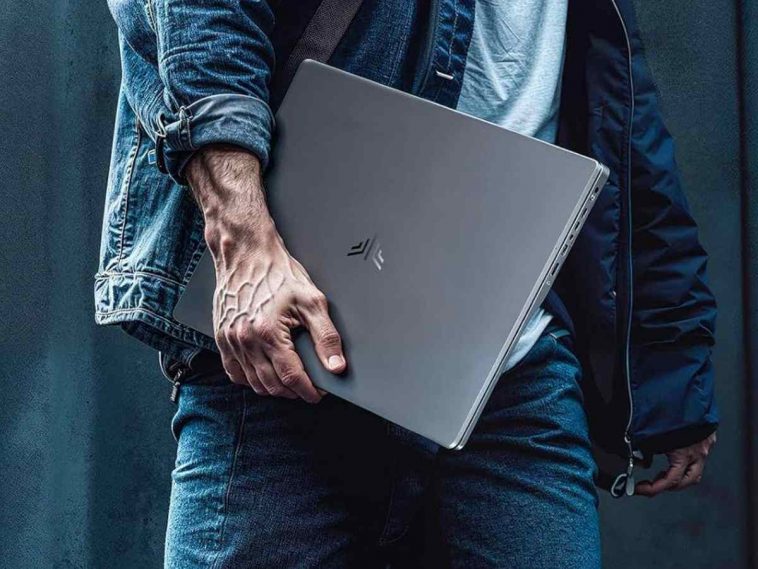 uomo cammina con laptop sotto braccio