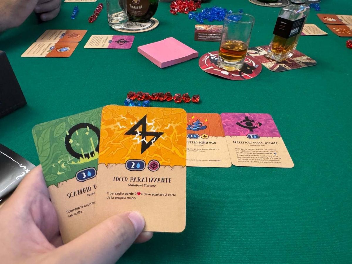 Dettaglio delle carte di gioco di Not Enough Mana con il tavolo imbandito con alcol e bicchieri pieni