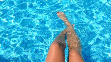 Le gambe di una ragazza a mollo nell'acqua di una piscina