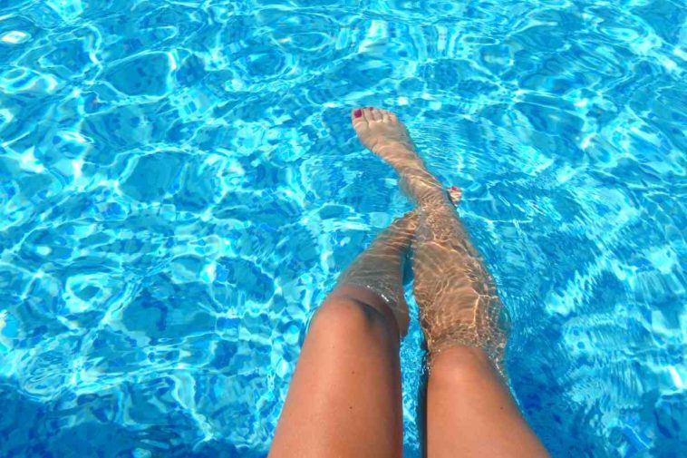 Le gambe di una ragazza a mollo nell'acqua di una piscina