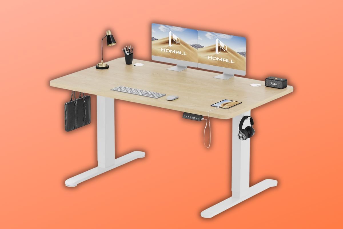 scrivania regolabile Homall con sopra due schermi, microfono, tastiera e borsa appesa