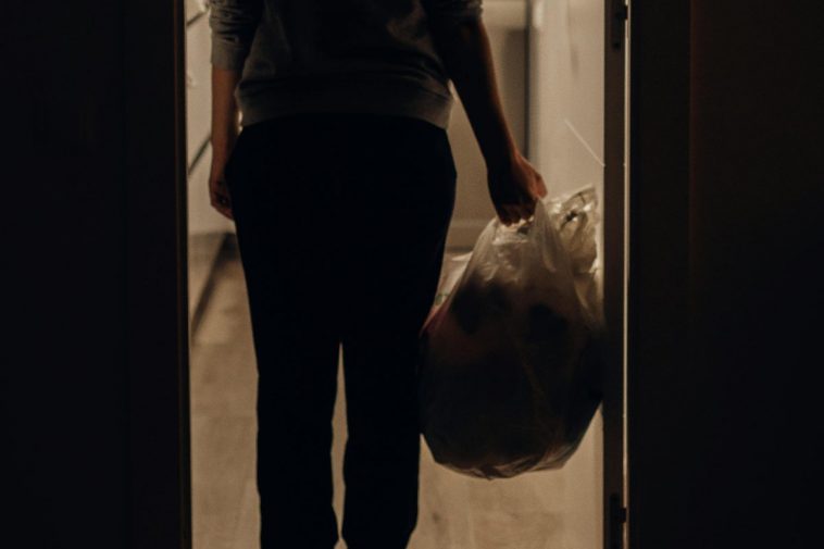 Una persona che si accinge a buttare un sacco della spazzatura