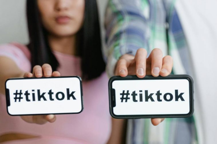 Due ragazzi mostrano i telefoni con la scritta TikTok