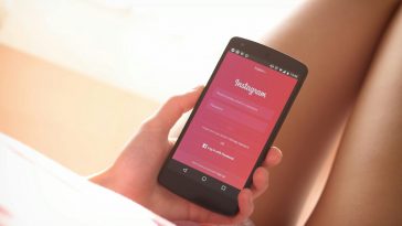 Una ragazza tiene in mano un telefono collegato alla pagina login di Instagram