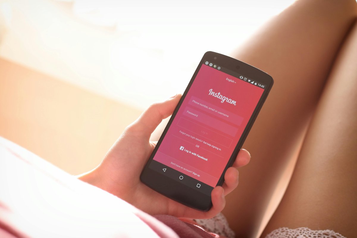 Una ragazza tiene in mano un telefono collegato alla pagina login di Instagram
