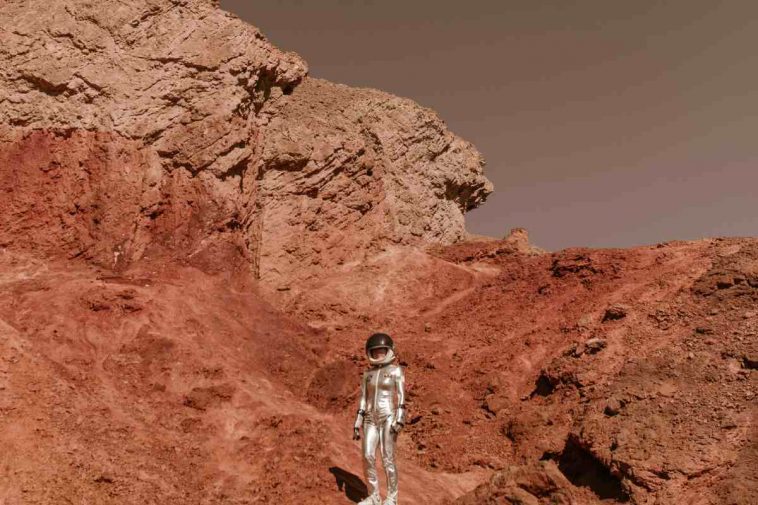 Un astronauta su un terreno rosso simile a Marte