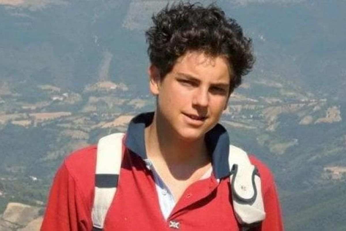 carlo acutis con maglia rossa in montagna