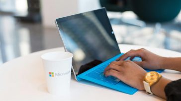 Un portatile blu con un contenitore del caffè con la scritta Microsoft