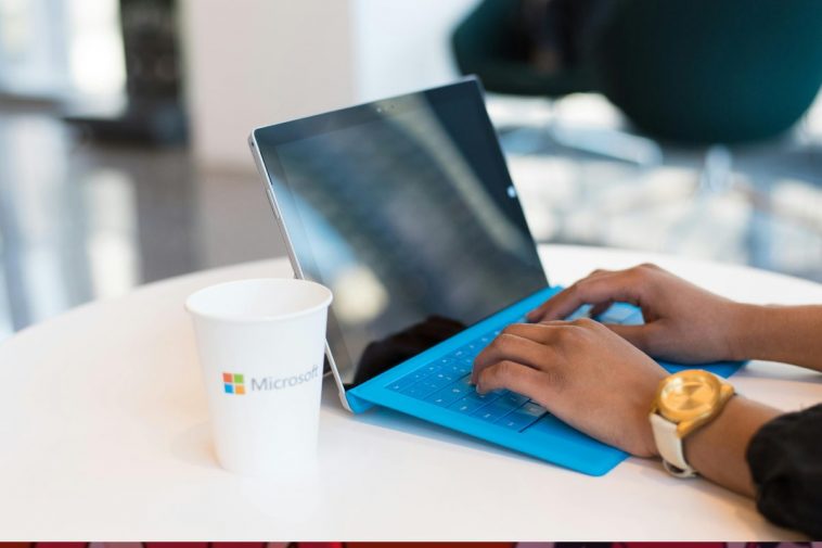 Un portatile blu con un contenitore del caffè con la scritta Microsoft