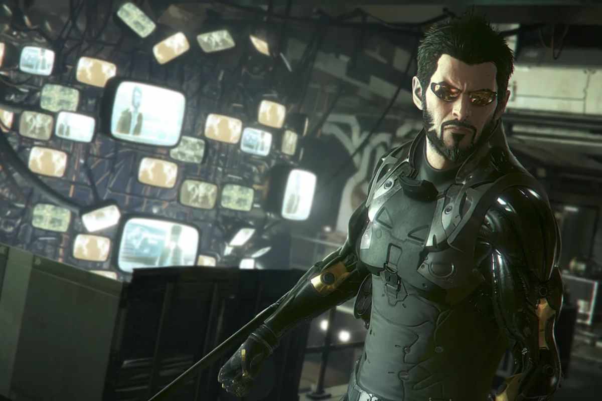 uomo con componenti cibernetici davanti a tanti chermi accesi