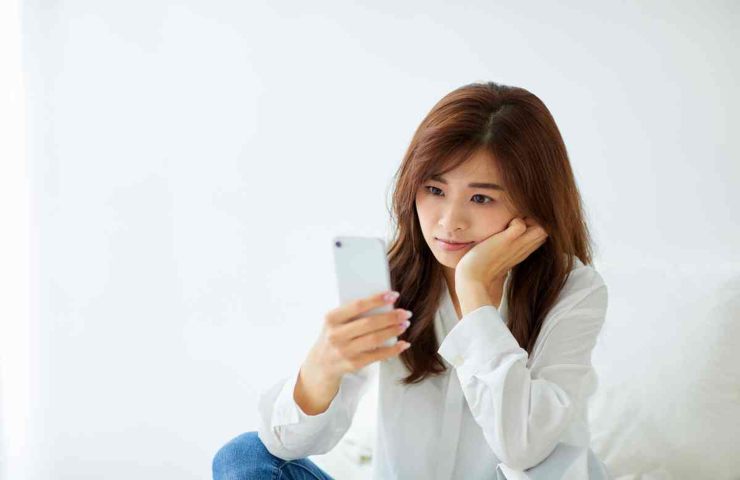 donna che guarda il telefono perplessa