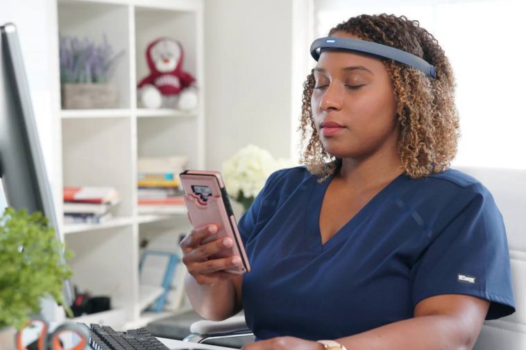 Una donna con la fascia FocusCalm e un telefono in mano