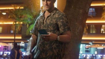 uomo in camicia con smarthphone in mano appoggato ad albero