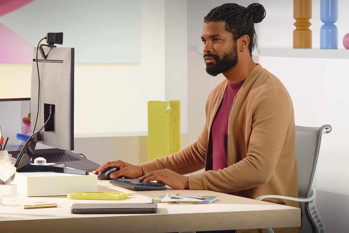 persona conc capelli e barba lunghi seduto alla scrivania che utilizza il mouse davanti a schermo PC