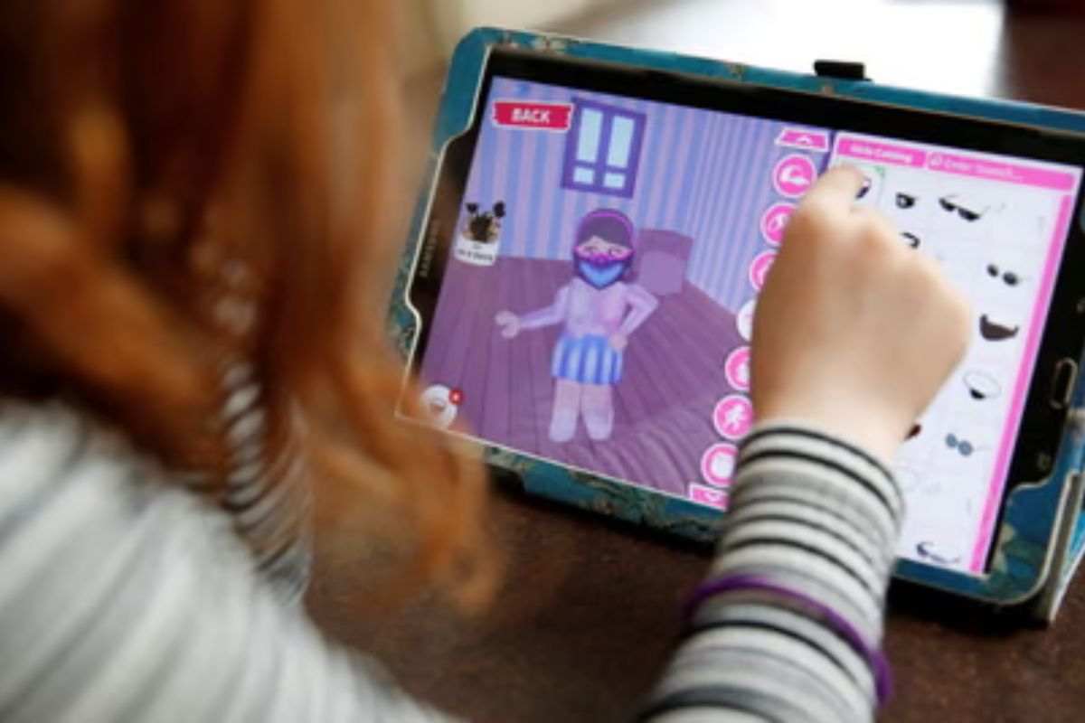 bambina gioca a roblox su tablet, immagine personaggio di roblox femminile che cambia abiti