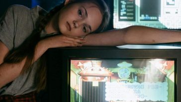 Una ragazza sconsolata appoggiata a un vecchio televisore