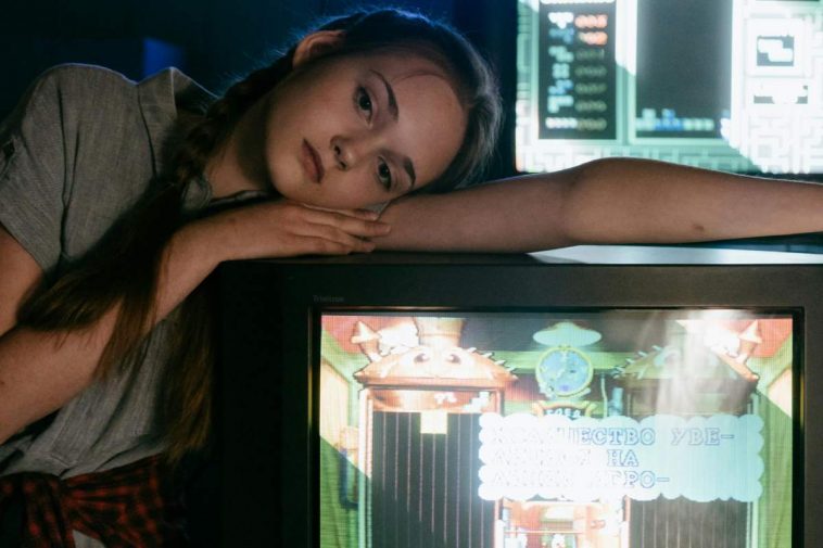 Una ragazza sconsolata appoggiata a un vecchio televisore