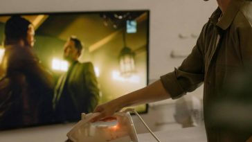 Una ragazza stira davanti alla tv accesa