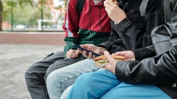 Ragazzini seduti su una panchina che guardano uno smartphone