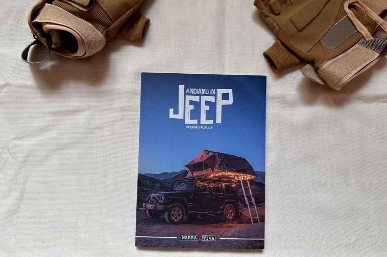 Un manualetto con la scritta andiamo in jeep e in copertina una jeep caricata per un campeggio e due guanti presenti sullo sfondo