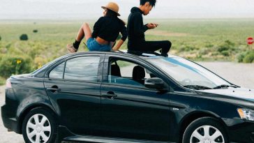 Due ragazze sedute sul tettuccio di un'automobile