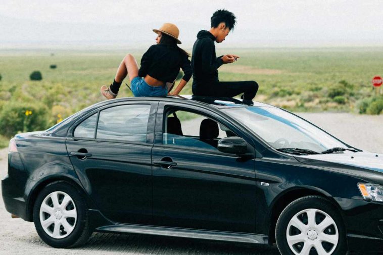 Due ragazze sedute sul tettuccio di un'automobile