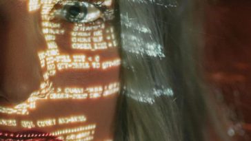 Una ragazza sul cui volto sono proiettati dei codici informatici