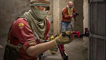 uomo con fazzoletto a coprire la testa co fucile in mano, alle spalle uomo a viso scoperto con fucile in mano