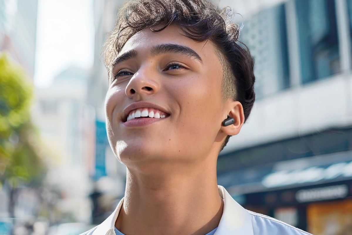 ragazzo con capelli neri che sorride mentre indossa auricolari neri
