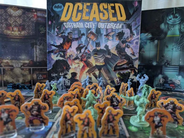 DCeased: Gotham City Outbreak, cover del gioco al centro con intorno le miniature presenti nella scatola