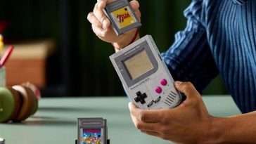 Lego game boy costruito, cartucce game boy tenute in mano da persona che la mette dentr gameboy