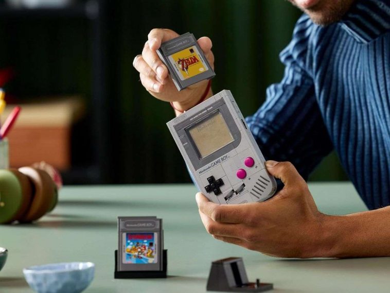 Lego game boy costruito, cartucce game boy tenute in mano da persona che la mette dentr gameboy