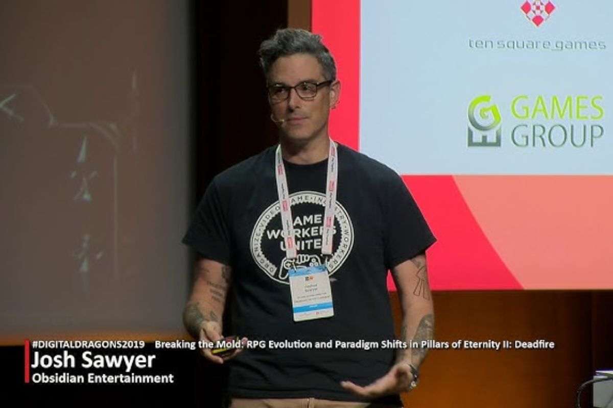 josh sawyer con badge al collo durante conferenza